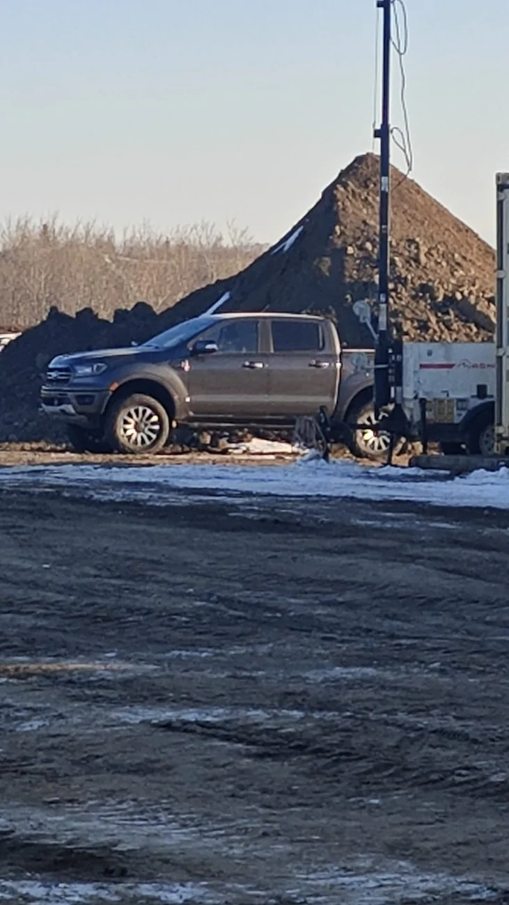 Parked by a Dirt pile and Light Tower.webp